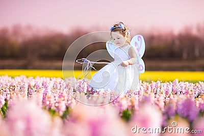 Toddler girl in fairy costume playing in a flower field