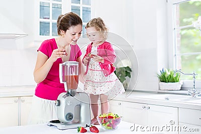 Toddler girl and her mother making fresh strawberry