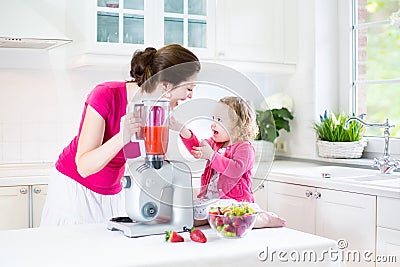 Toddler girl and her mother making fresh strawberry