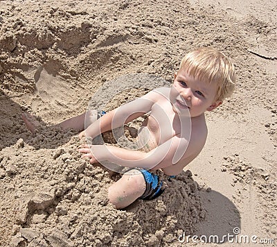 Toddler plays in sand at the beach