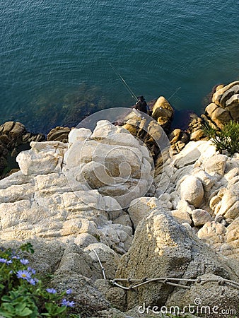 Top view of fisherman sitting on rocks with fishing rods