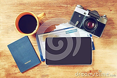 Top view image of tablet with empty screen, old camera passport and flight boarding pass