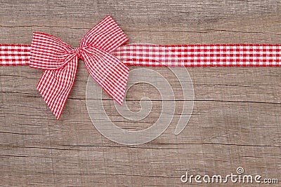 Top view of a red checked ribbon decoration on wooden background