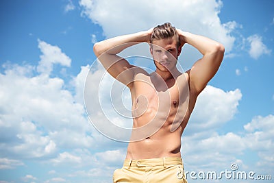 Topless man outdoor with both hands behind head