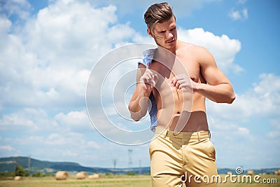Topless man outdoor looks down with straw in hand