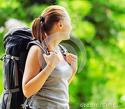 Young woman with backpack in a woods. Hiking at su