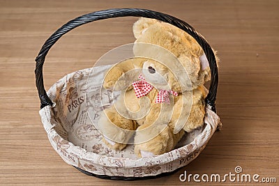Toy teddy bear in basket isolated on wooden desk