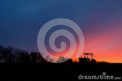 Tractor and tree line at sunset against the sky