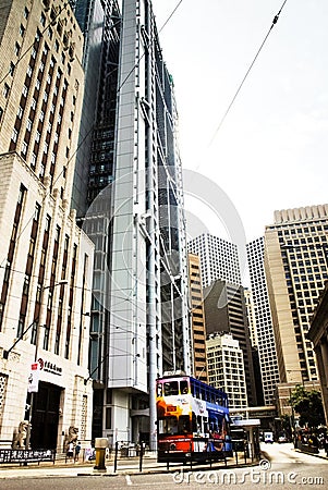 A tram carrying passengers passes by the Bank of China building.