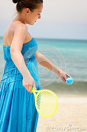 Woman in blue dress playing tennis on the beach