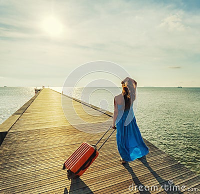 Young woman with suitcase waking on wooden pier