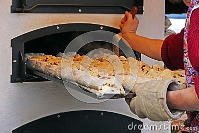A tray of filled bread is pushed into the baking oven