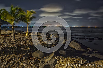 Tropical beach at night with city lights in background - HDR