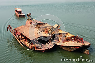Tugboat pulling barge of sand
