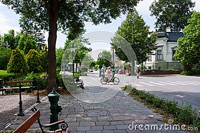 Lady rides a bicycle on a green street of a town
