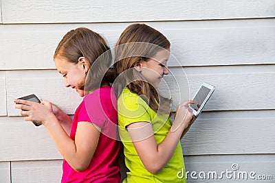 Twin sister girls playing with tablet pc happy on white wall