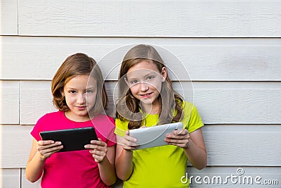 Twin sister girls playing with tablet pc happy on white wall