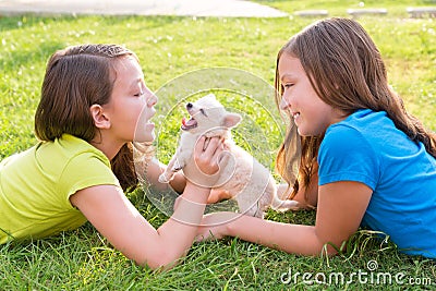 Twin sister kid girls and puppy dog lying in lawn