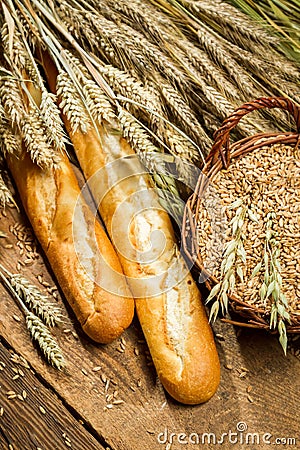 Two baguettes and a basket full of grain with ears