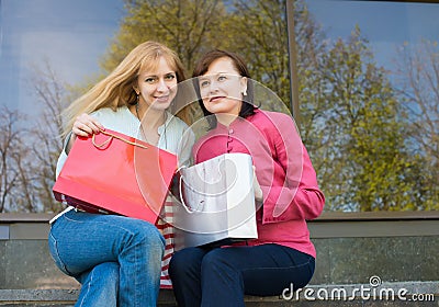 Two beautiful happy women with shopping bags near clothes store.