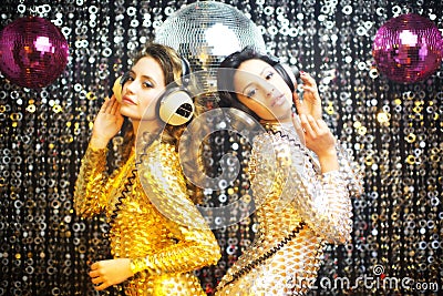 Two beautiful sexy disco women in gold and silver catsuits danci