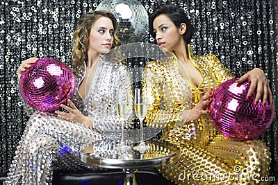 Two beautiful sexy disco women in gold and silver catsuits danci