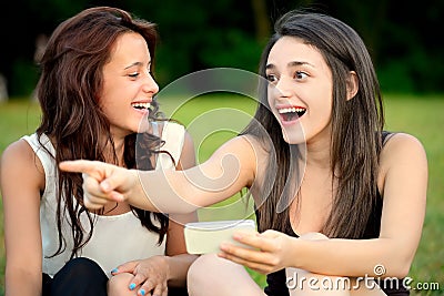 Two beautiful young amazed women pointing outside