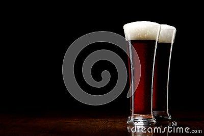 Two Beer into glass on a black and wooden table