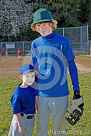 Two brothers wearing baseball uniforms.