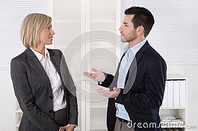 Two business people working in a team talking together in the of