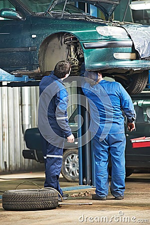 Two car mechanic diagnosing auto suspension