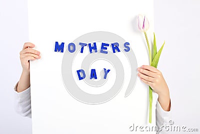 Two childhood hands holding white board with blue text Mothers day and one white and violet tulip