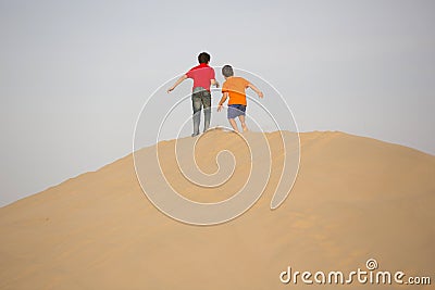 Two children play in the sand of desert