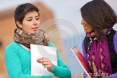 Two college students at park with books on hands