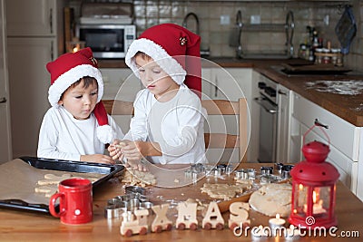 Two cute boys with santa hat, preparing cookies in the kitchen