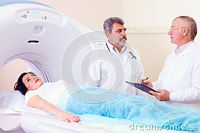 Two doctors preparing patient to CT scanner procedure