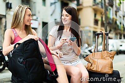 Two female travellers using smartphone navigating system