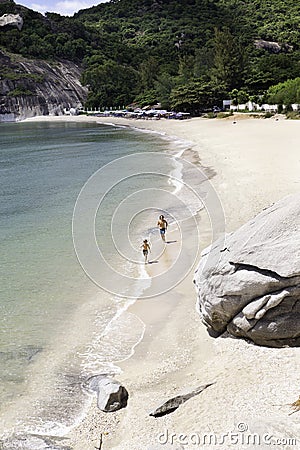 Two figures running on empty beach