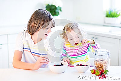 Two funny siblings having fruit for breakfast drinking juice