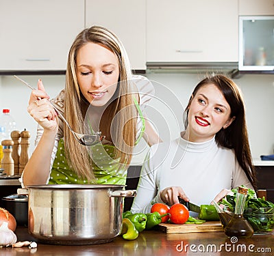 Two girlfriends cooking with vegetables