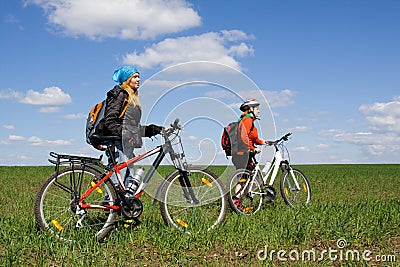 Two girls on bicycles in the countryside.