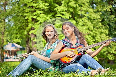 Two girls playing guitar and flute in the park