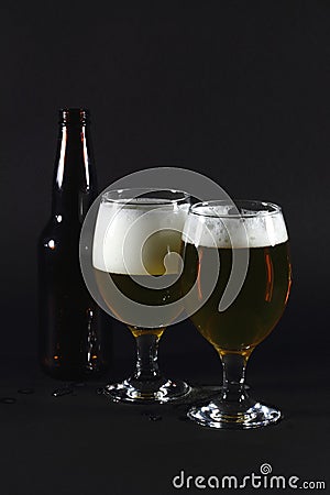 Two glasses full with beer and beer bottle.