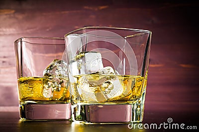 Two glasses of whiskey with ice on old wood table