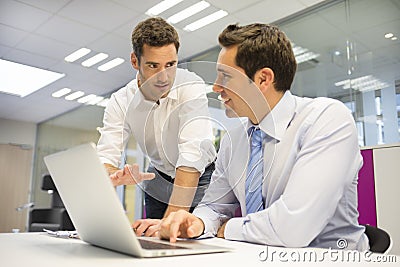 Two handsome businessmen working together on a Laptop in the off