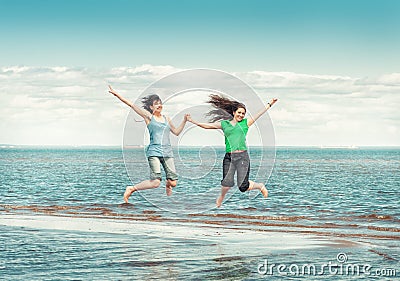 Two happy women jumping in the water of sea