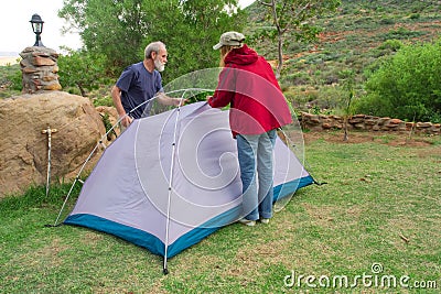 Two hikers assemble tents on camping site