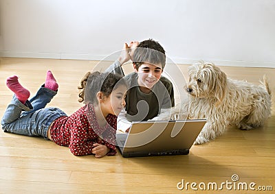 Two kids with laptop computer and a dog