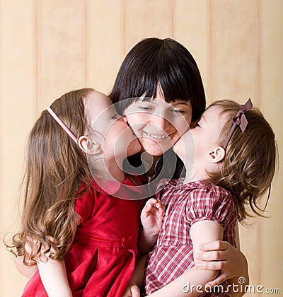 Two little daughter kiss their mother