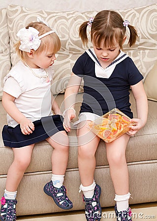 Two little girls eat candies